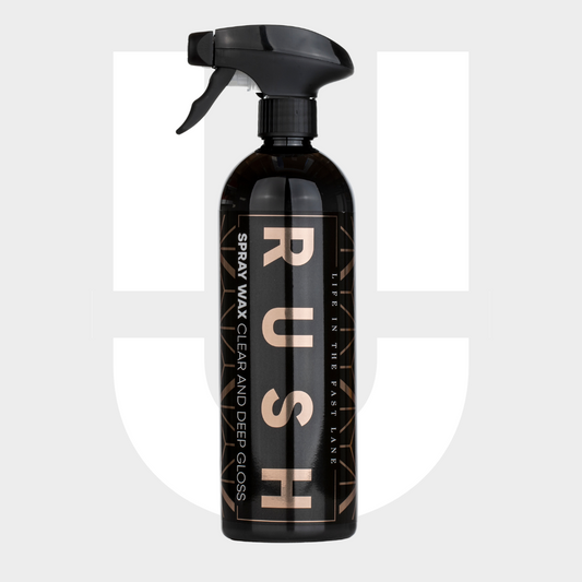 A black spray bottle labeled 1+1 GRATIS Spray Wax, designed with nanotechnologie for lak bescherming, stands upright on a light gray background with a faint logo behind it.