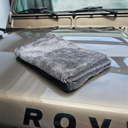 Een opgevouwen grijze microvezel droogdoek 600 GSM rust op de motorkap van een tan voertuig met ROV zichtbaar in zwarte letters.
