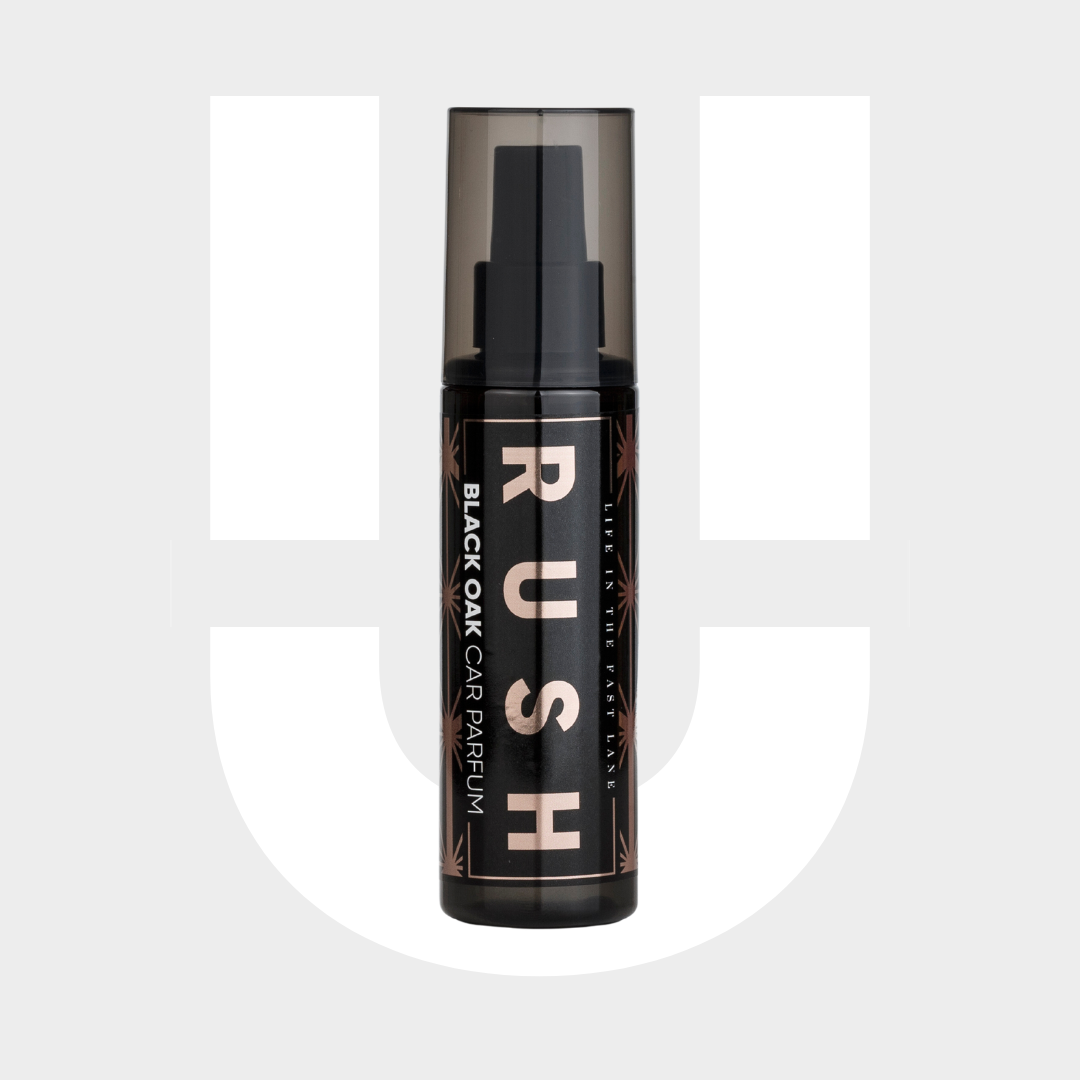 Een zwarte spuitflacon met het label RUSH Black Oak Auto Parfum staat tegen een grijze en witte achtergrond, perfect voor langdurig ruikbaar ruiken.