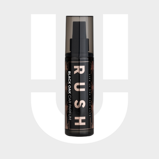 Een zwarte spuitflacon met het label RUSH Black Oak Auto Parfum staat tegen een grijze en witte achtergrond, perfect voor langdurig ruikbaar ruiken.