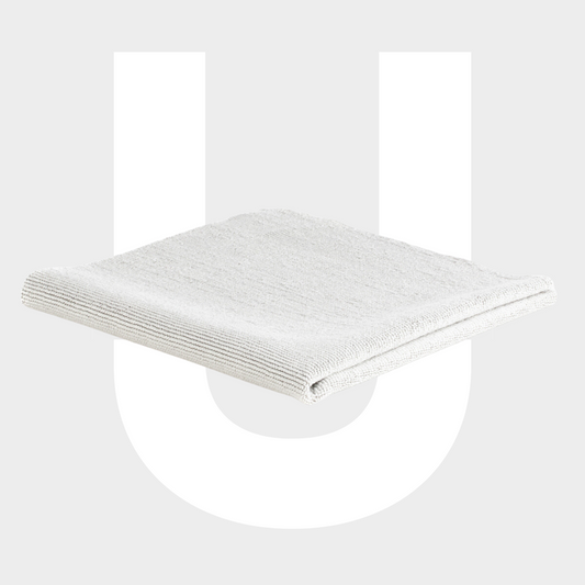 Een netjes gevouwen wit microvezeldoekje staat centraal op een grijze achtergrond met een grote witte letter U erachter.