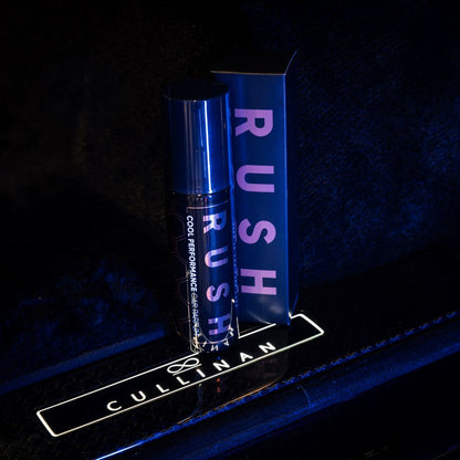 Een fles en doos met het label RUSH Cool Performance autoparfum rusten op een verlichte CULLINAN auto dorpel, tegen een donkere achtergrond.