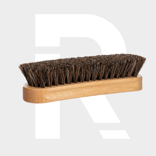 The Leather Cleaning Brush features a wooden handle and dense, dark paardenharen borstel bristles, shown on a light gray background with a large white letter R partially visible behind it.
