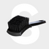 The Tire Brush, featuring a black design with stiff bristles and a curved handle for optimal banden reinigen, is shown on a light gray background with a large white letter S behind it.