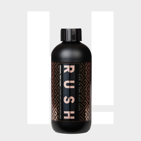 Een zwarte fles met het label RUSH met een geometrisch patroon, ideaal voor teak reinigen, staat rechtop tegen een lichtgrijze achtergrond.