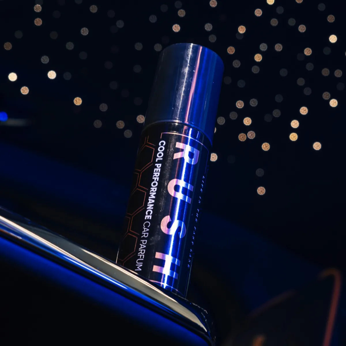 Een bus met het label RUSH Cool Performance auto parfum wordt weergegeven tegen een donkere achtergrond met sterren en een reflecterend oppervlak.