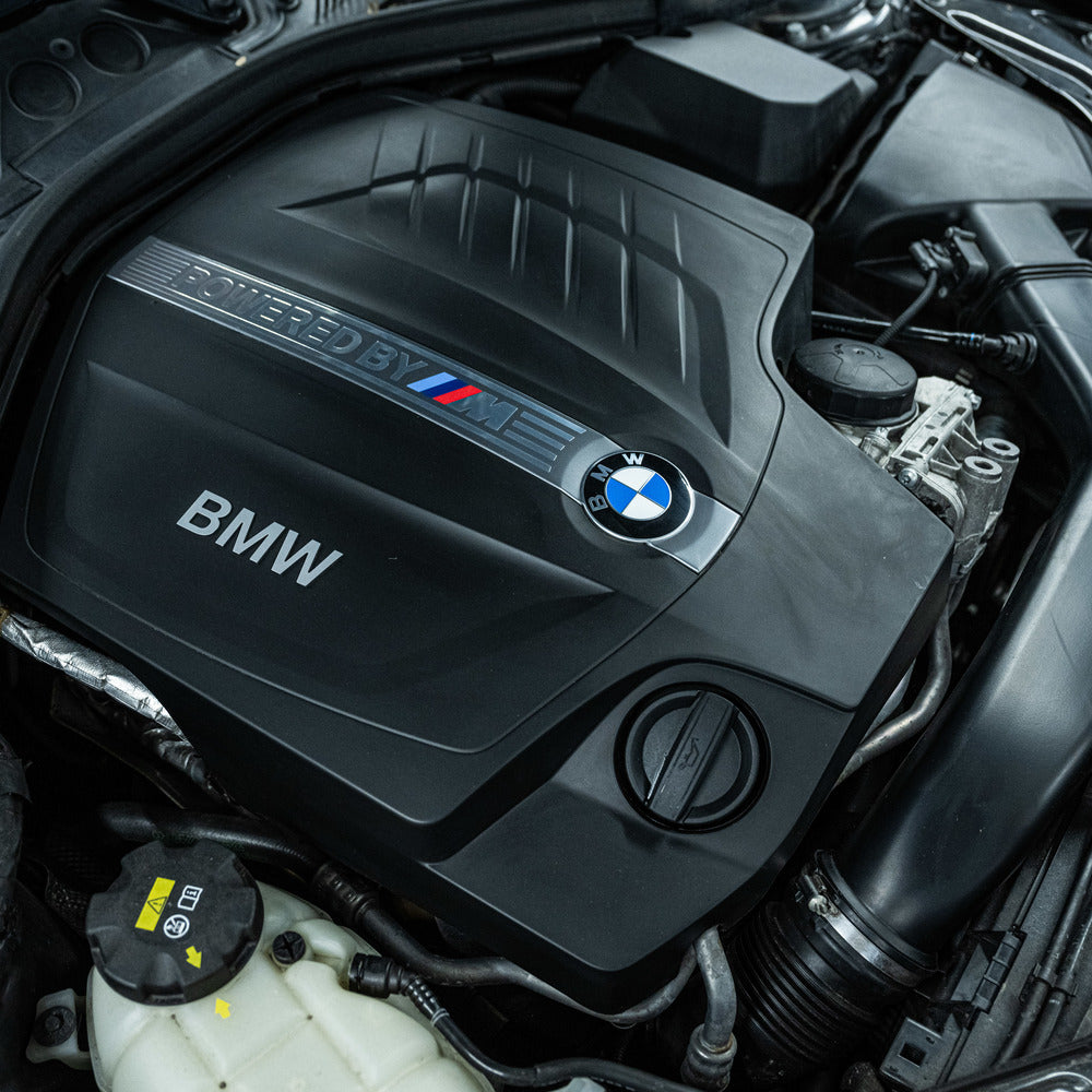 Close-up van een BMW motor met het Powered by M embleem, vers gedetailleerd met RUSH Engine Cleaner voor motorruimte reiniging.