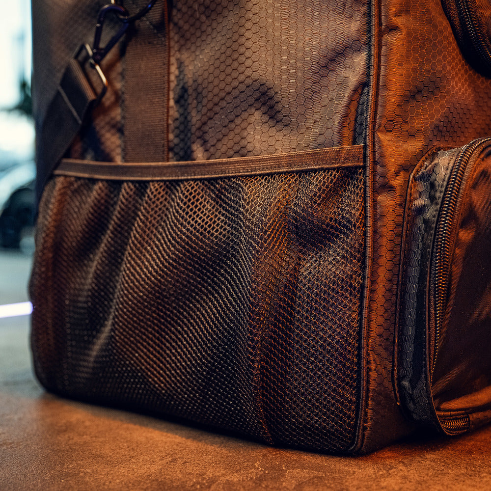Close-up van de RUSH Detailing Bag, een ruime opbergtas met hexagonpatroon, ritsvak en mesh zijvak op een bruine ondergrond.