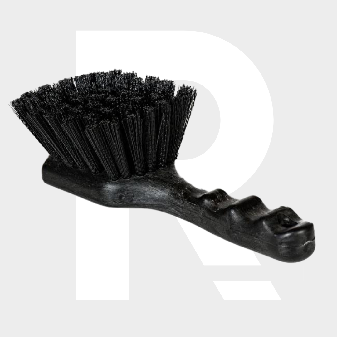 Een zwarte harde borstel met een voorgevormd plastic handvat rust op een lichtgrijze achtergrond.
