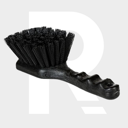 Een zwarte harde borstel met een voorgevormd plastic handvat rust op een lichtgrijze achtergrond.