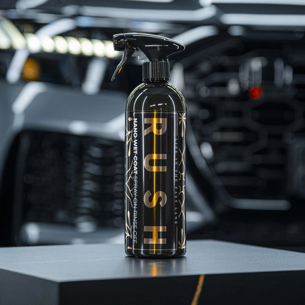 Een zwarte fles spuitwas met het label PUSH staat op een reflecterend oppervlak en belooft een extreem waterparelend effect met een vage auto op de achtergrond.