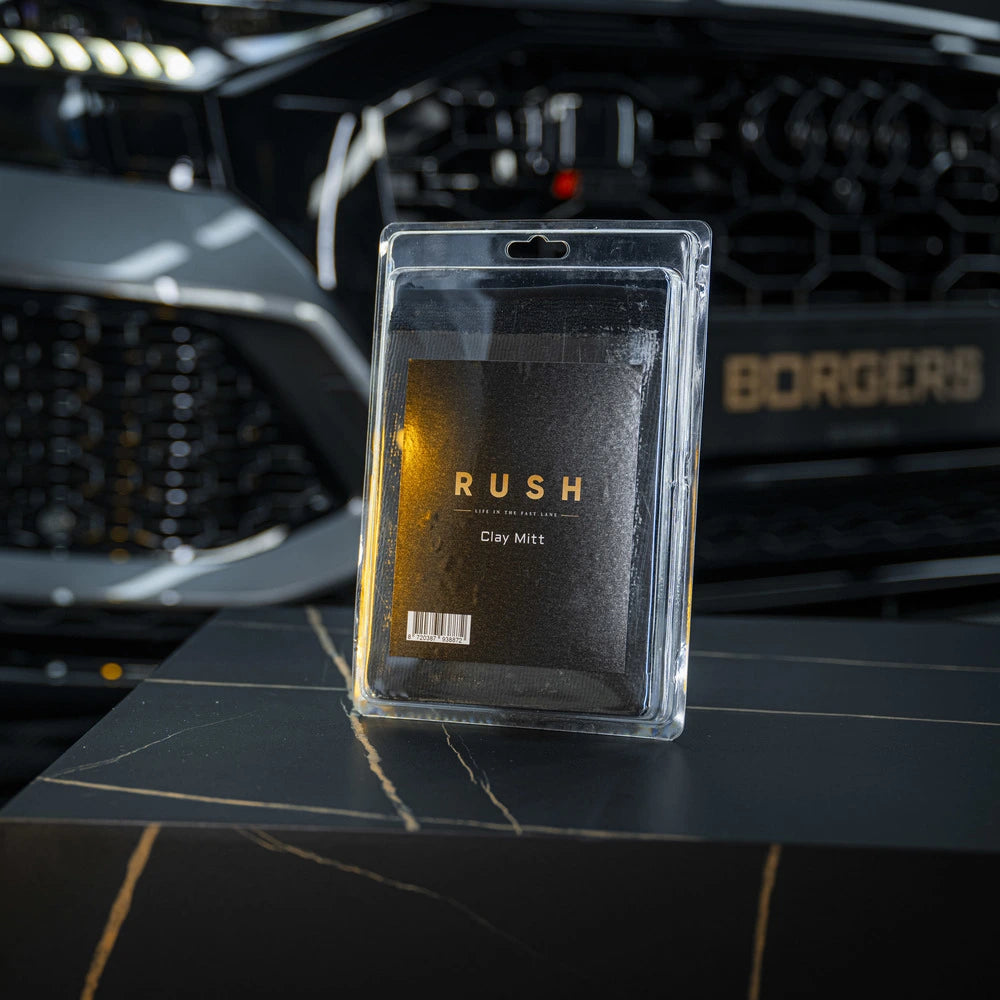 A packaged Clay Mitt is shown on a black marble surface with a blurred luxury car grille and BORGERS logo in the background—ideal for lak reinigen and taking your car care to the next level.