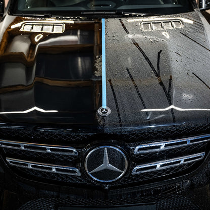 A black Mercedes-Benz hood split by blue tape demonstrates the Ceramic Sealant Package: the left side shines with paint protection, while the right stays dirty and covered with water spots.