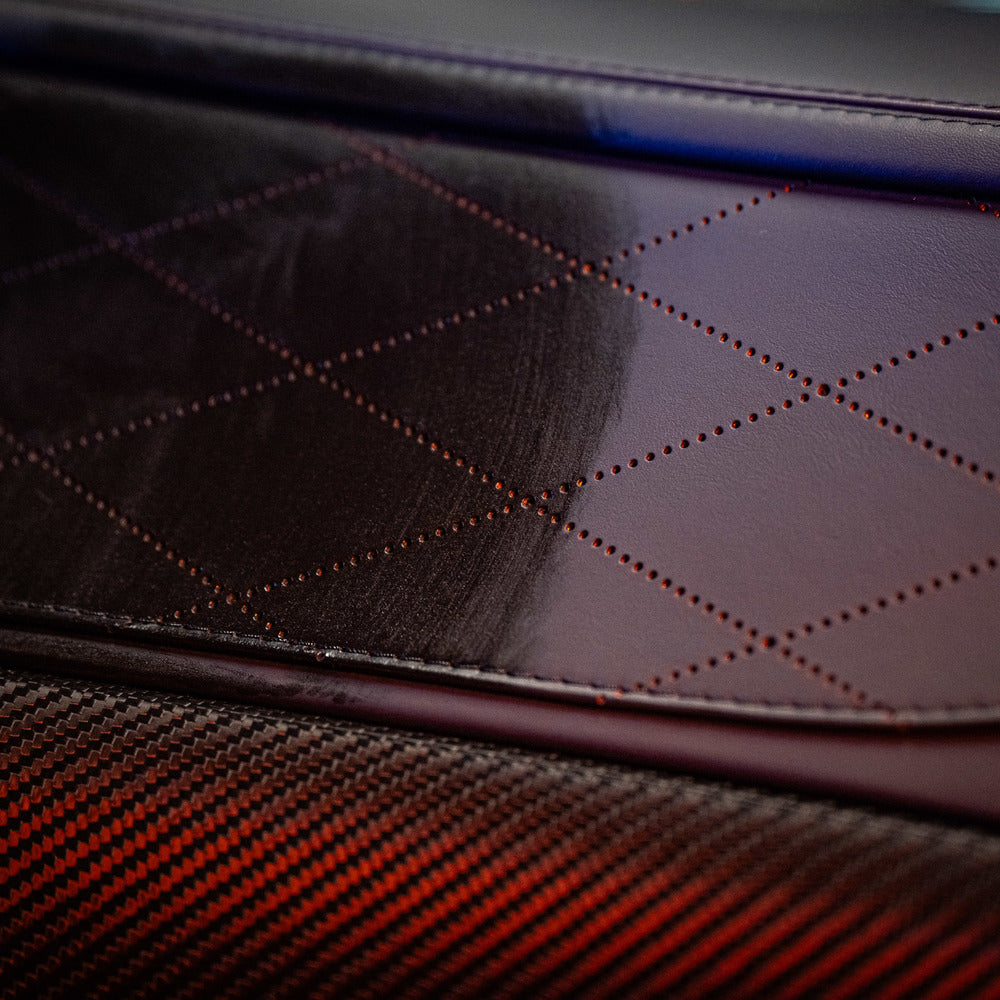 Close-up van een auto-interieur met ruitgestikt bruin leer en een koolstofvezelpaneel, behandeld met interieurverzorgingsspray voor interieur beschermen auto.