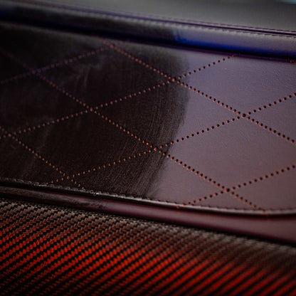 Close-up van een auto-interieur met ruitgestikt bruin leer en een koolstofvezelpaneel, behandeld met interieurverzorgingsspray voor interieur beschermen auto.