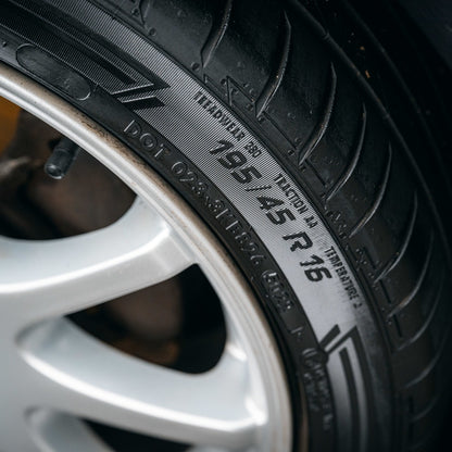 Close-up van een autoband en zilveren velg, ideaal voor het demonstreren van het gebruik van een bandenzwart applicator op zijwandmarkeringen en specificaties.