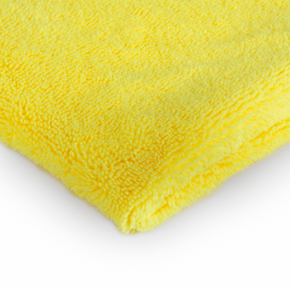 Een gevouwen geel microvezeldoek auto interieur op een wit oppervlak, dat het zachte en gestructureerde materiaal benadrukt.