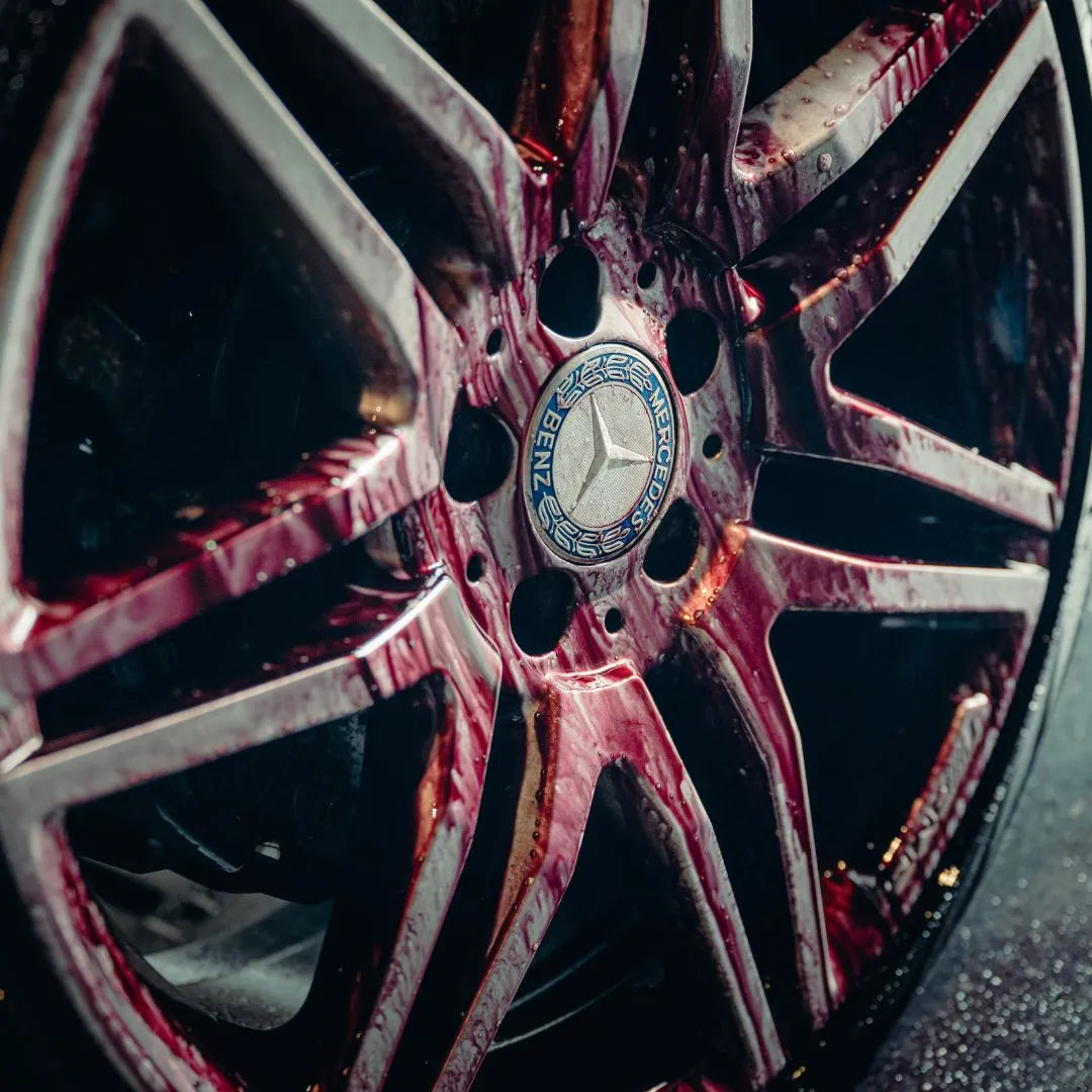 Close-up van een Mercedes-Benz velg met roodachtige vloeistof, mogelijk remstofverwijderaar, langs de spaken van de velg.