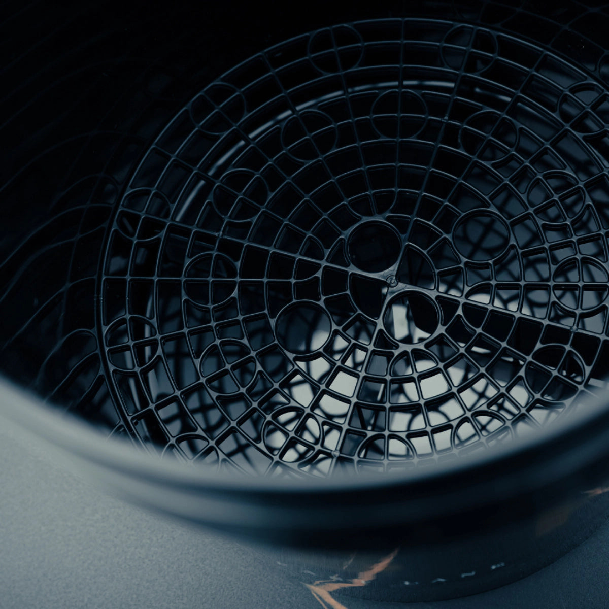 Een close-up van een zwarte ronde gritbeschermer in een detailingemmer, mogelijk gebruikt voor autowassen of keukenapparatuur.