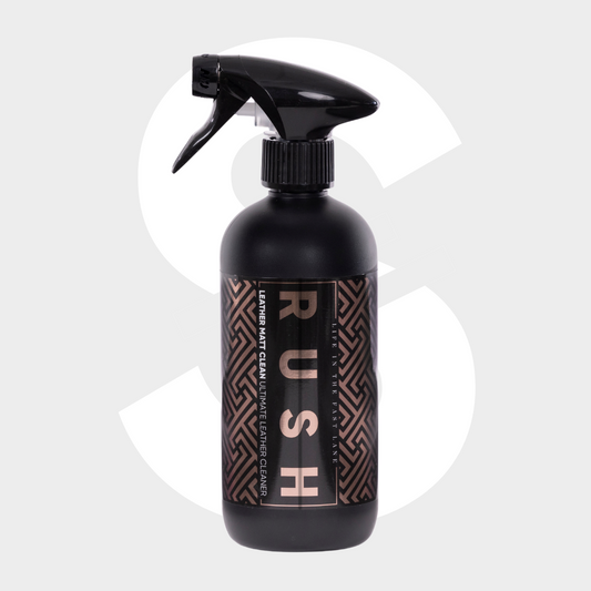 A black spray bottle labeled "Leather Matt Clean" with a geometric pattern sits on a light gray background featuring a large faded dollar sign—ideal for cleaning lederen autobekleding and achieving a matte finish.