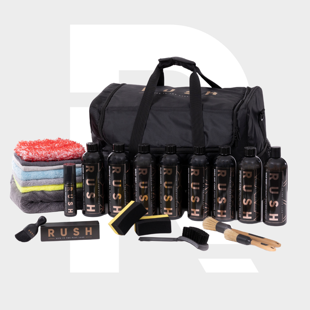 The Detailing Package PLUS | 23-delig includes a Detailing Bag, black RUSH bottles, brushes, sponges, assorted microfiber cloths, and a spray bottle—everything arranged neatly for complete car care.