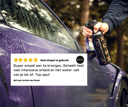 Een hand spuit RUSH spraywax op een natte, paarse auto, met op de voorgrond een Nederlandse recensie met vijf sterren en het waterafstotende effect.