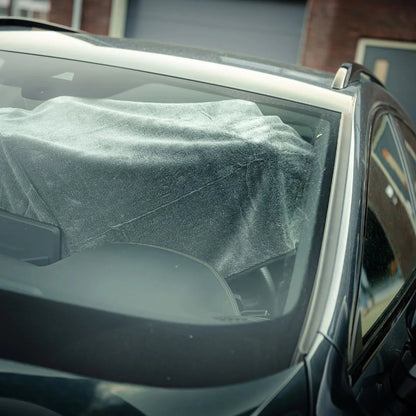 Blik door de voorruit van een auto met een grote grijze doek op het dashboard, klaar voor gebruik met de RUSH Window Clear Winter Kit of IJskrabber De-Icer.